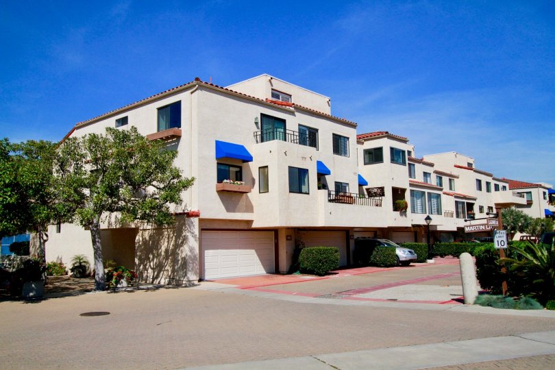 Broadmoor Huntington Harbor Huntington Beach California building light rose color paint front glass window balcony attached big tree front side