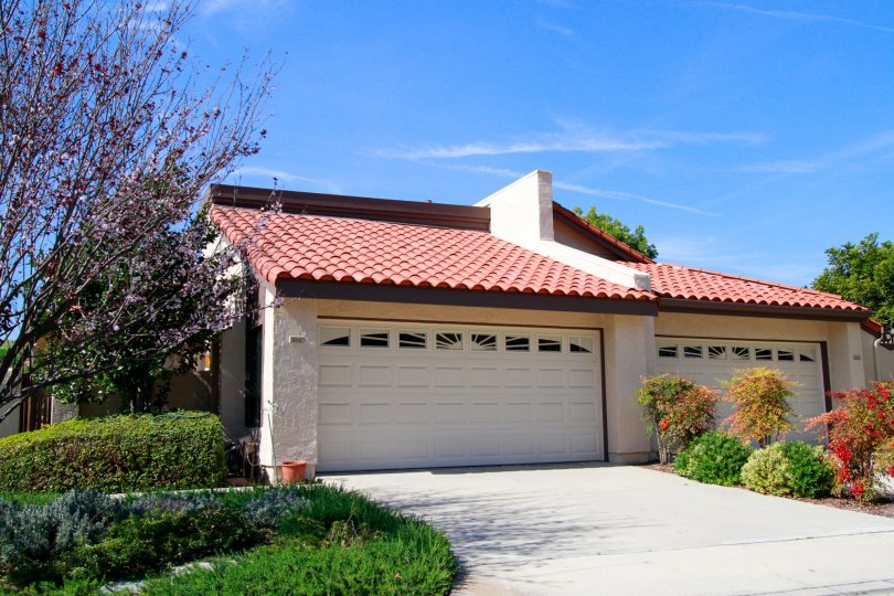 A house with big doors in the Landmark Yorktown with flowering plants, ornamental plants, trees and shrubs.