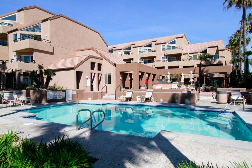 Apartments with a community pool and veranda that have lounge chairs and a hot tube.