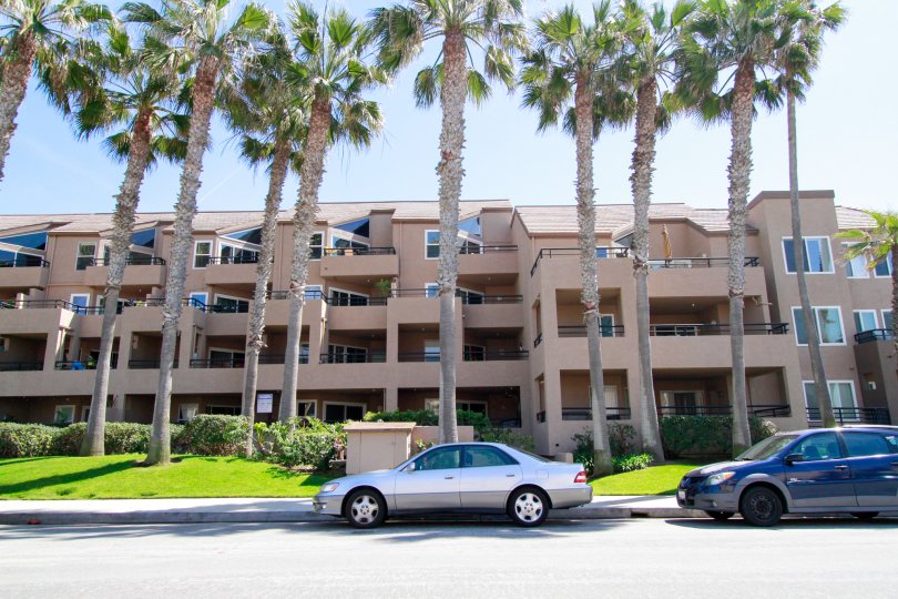 THE APARTMENT LOOKING SO LARGE AND IN FRONT OF BEAUTIFUL GARDEN AVAILABLE MORE TREES ALSO THERE AND TWO CARS PARKING IN FRONT OF THERE.