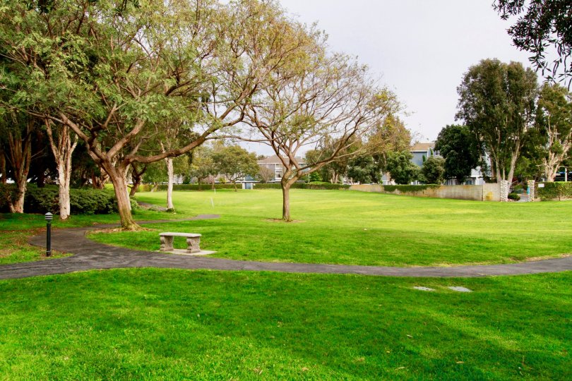 Seabridge Townhomes park with trees and a sidewalk on a cloudy day.