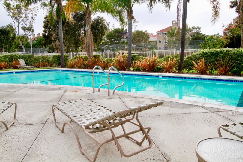 Seabridge Townhomes pool with deck chairs and a table on a cloudy day.