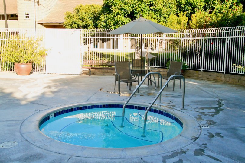 Seagate hot tub with deck chairs and an umbrella around it.