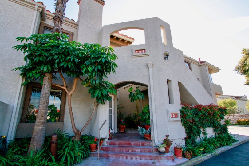 Tiara De La Pacifica two story apartments with trees and bushes on a sunny day.