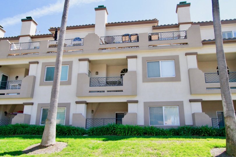 Excellent view of a lawn in front of Villas with balconies and palm trees in Vista of Catalina of Huntington Beach