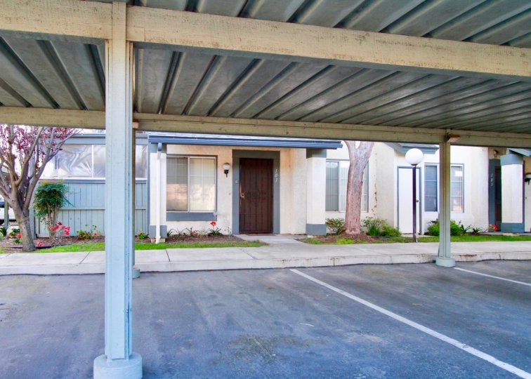 THE PARKING PLACE WITH A HOUSE AND SOME TREES ARE NEAR TO THE HOUSE THE HOUSE DOOR CLOSED AND FLOWER PLANTS ALSO AVAILABLE.