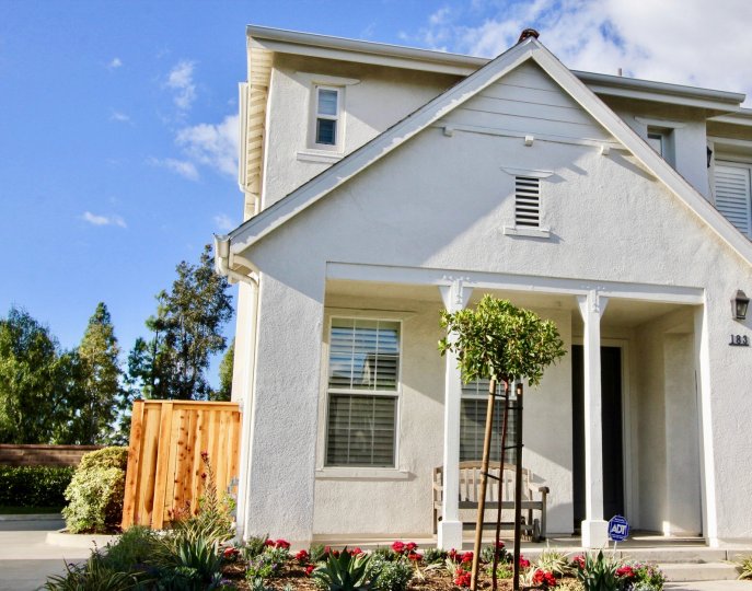 The front side of white color Arden Square with open door and flowering plants in front side