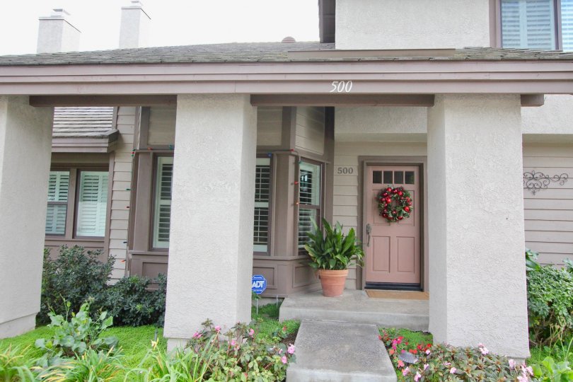 THE FRONT VIEW OF HOUSE WITH NUMBER ON THE WALL, PLANTS AND LAWN WHICH IS SITUATED IN THE CITY OF IRVINE