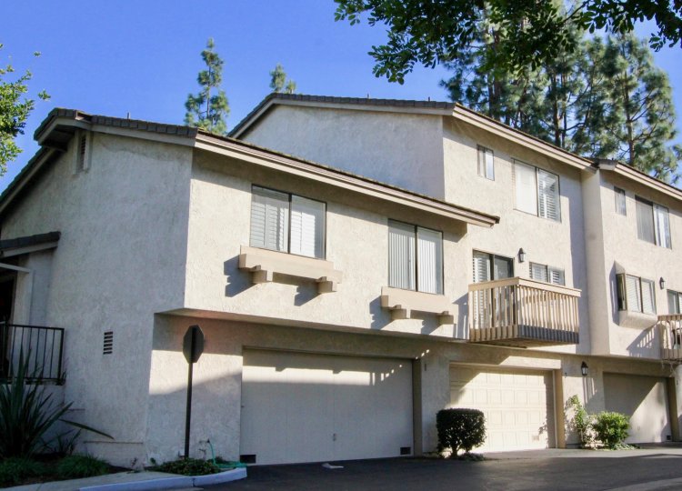 A simple low-rise housing in the Ridge Townhomes Bren community with sliding windows and closed carport.