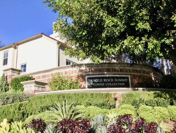 Security wall with community sign on top of a hill outside Summit Towne Collection in Irvine CA