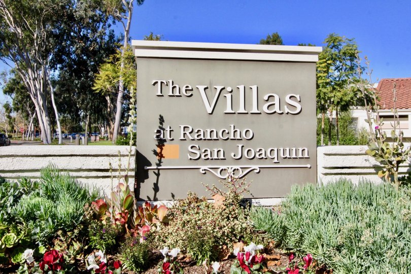 A large gray and white sign behind a garden at Villas at RSL in Irvine CA