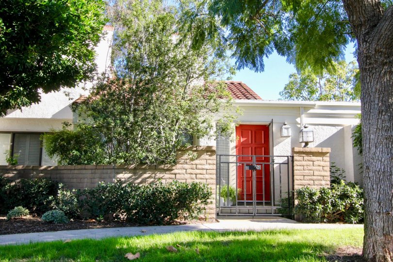 A front view a home with a bright red door in the Villas at RSJ community on a sunny day