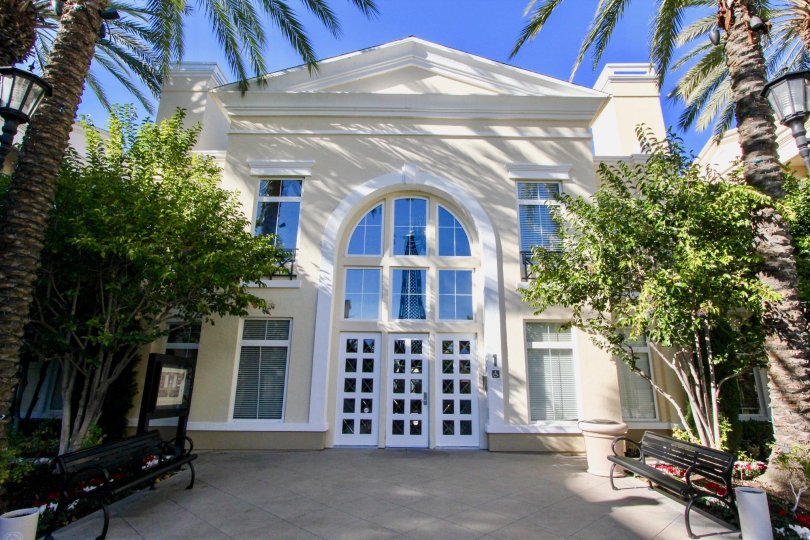 Large white building with benches and various trees out front