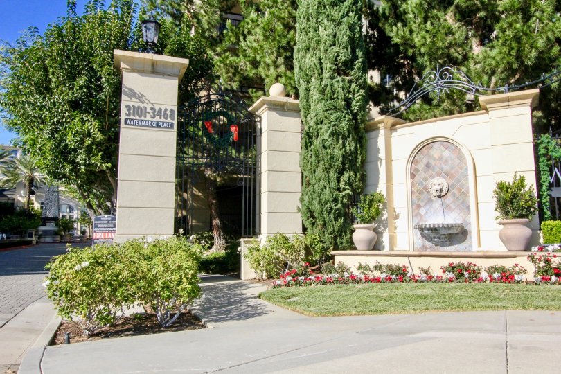The entrance post to Watermarke with flowers, trees and fountain