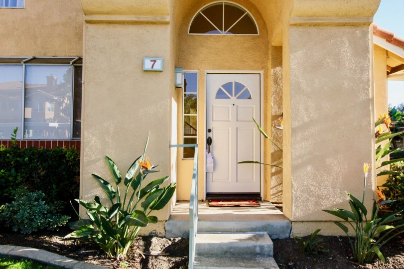 A bright yellow stucco house with a white door and the house number 7 painted on the front porch in Irvine, CA.