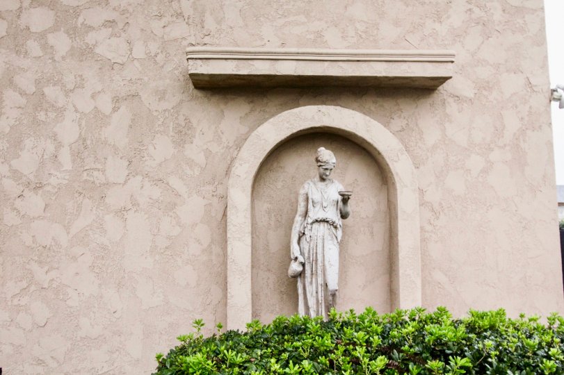 a pleasant day in the la venezia with wall that has statue in it and also plants below the statue