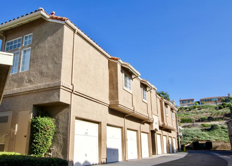 A tall hedge sits tucked into an indent in a tan building in the Village Niguel Terrace II community