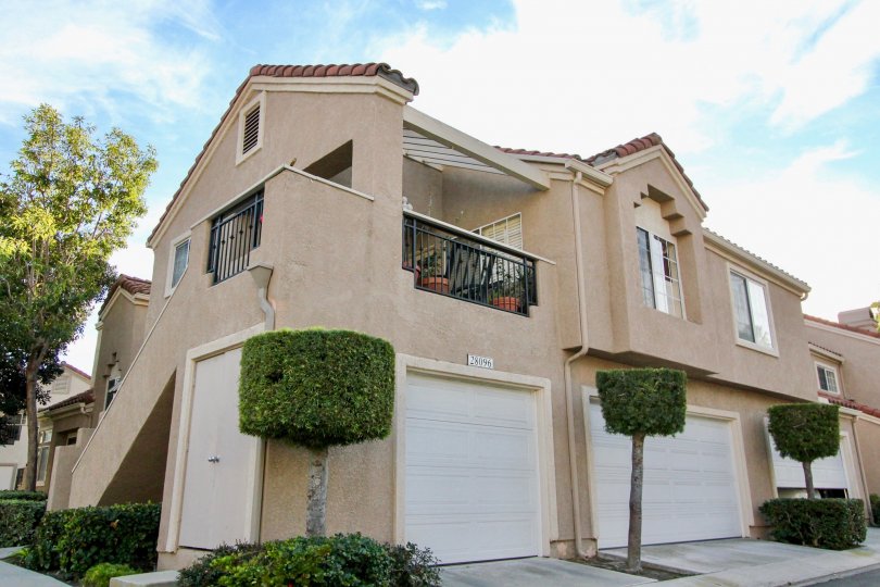 Small trimmed trees stand next to garage doors of the Palm Garden units in Mission Viejo, California.