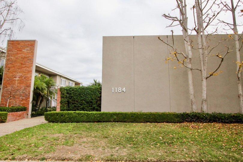 a warm day in the newport garden villas witha building that has large compound wall that is numbered as 1184