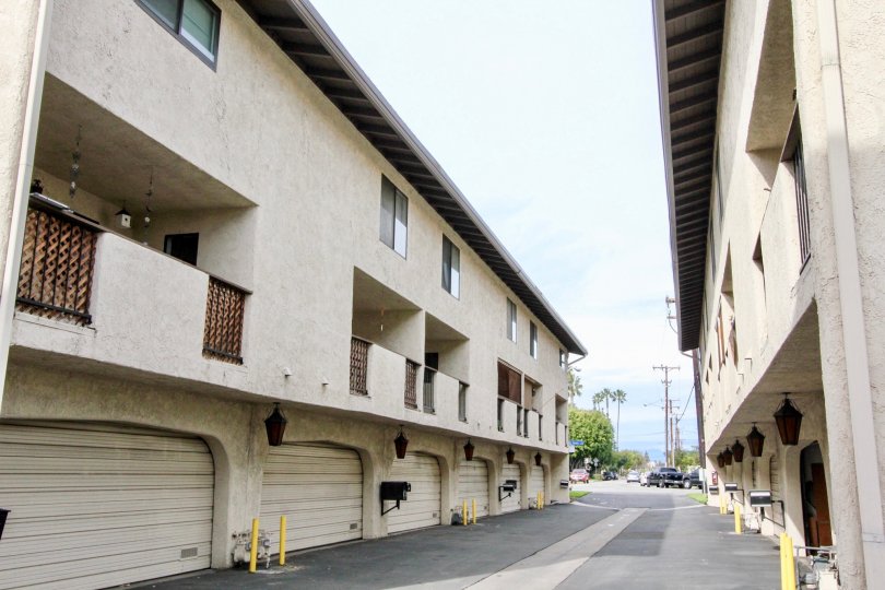 A street dividing buildings in Manana Townhomes with garages on a sunny day