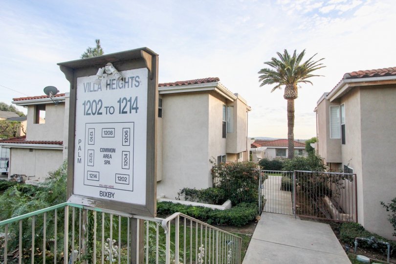 A sign and gated entrance to the Villa Heights community with bushes and palm tree