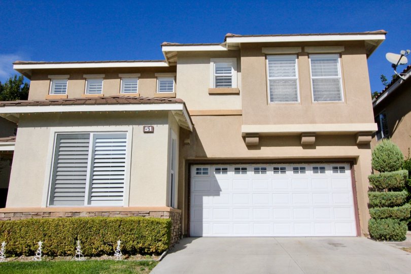 A spiraled tall hedge sits next to a garage in the Ballantree community