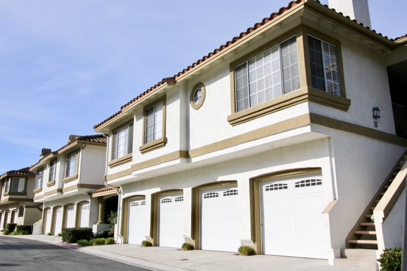 A street view of the private two garage parking at Casafina with light colored buildings and dark roof and trim
