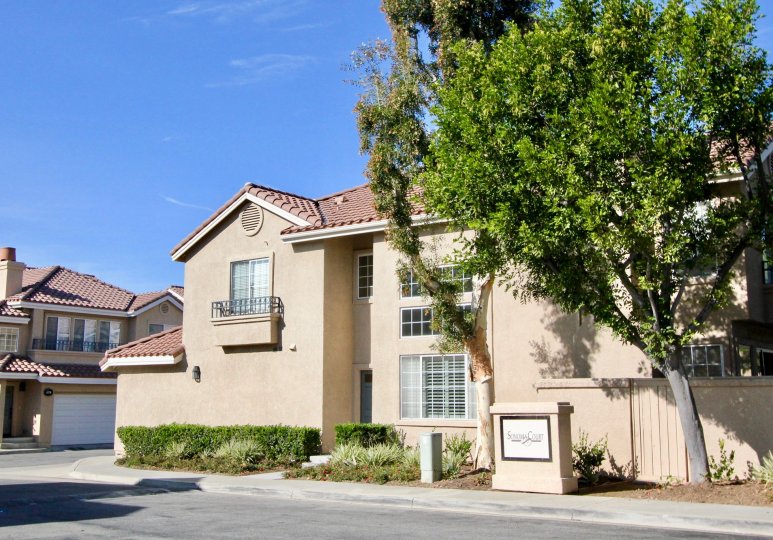 A sunny day by a Sonoma Court multiplex with a Sonoma Court sign in front of it in between two big trees