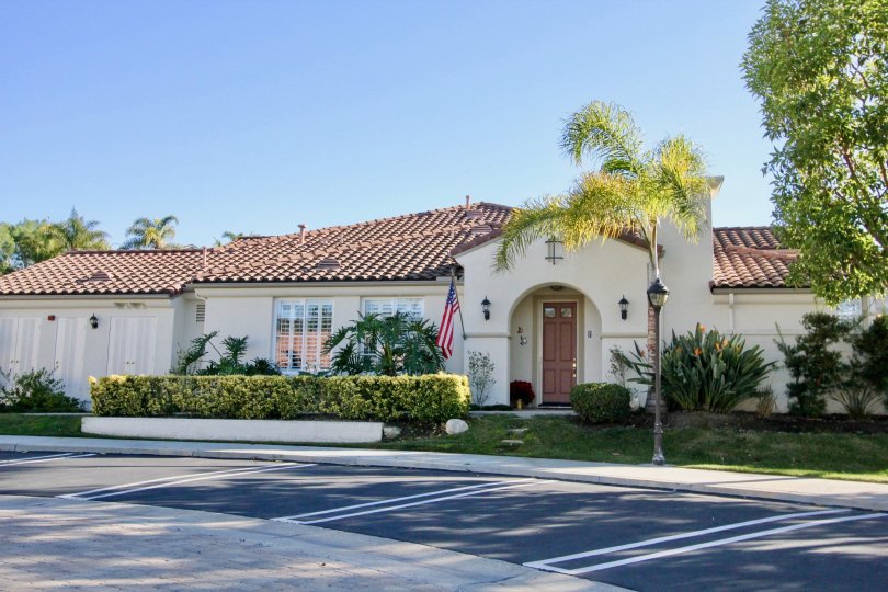 Arched portico with American flag and lawn with trees in Caramel.