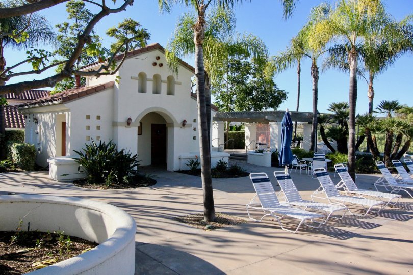 A beautiful house and it is surrounded with a set of trees and there is a set of chairs to have relax.