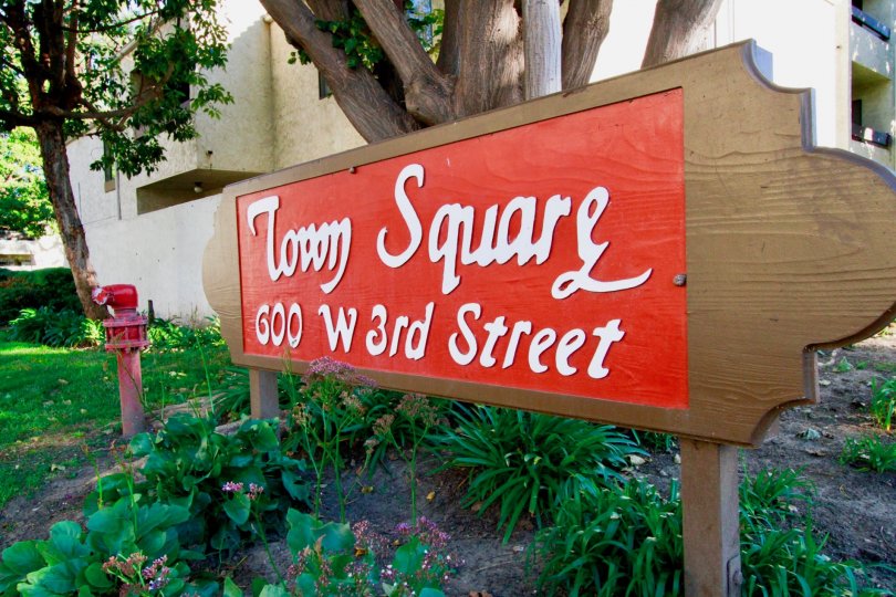the board at the entrance indicates the Town Square address placed between the plants and bushes