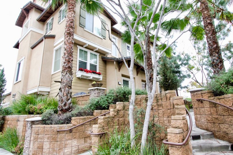 Decorative brick retaining walls with stone pathways lined by mature trees outside Arbor Walk two storey homes