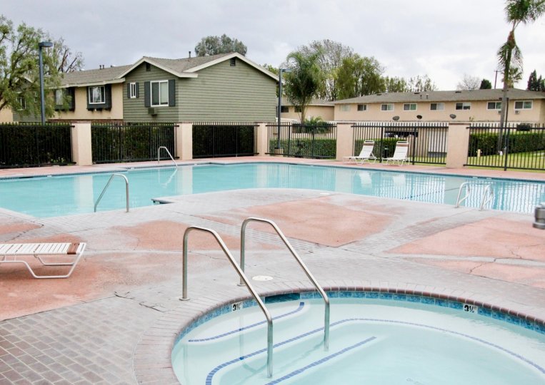 Resident's pool and hot tub in Influential Square in Tustin, California. Fenced pool area and lounge chairs around pool.