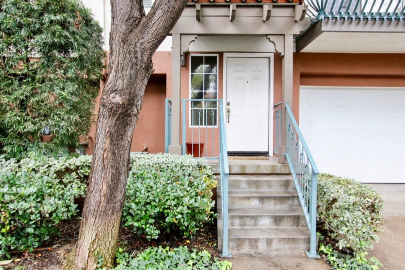 An empty red planter sits next to a white door in the Tustin Del Verde community