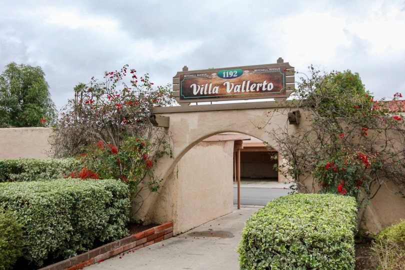 A sunny day showing the entrance to the private parking at Villa Vallerto with flowers and green bushes