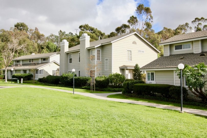 There are three houses and has meadow, light lamps, trees and plants near and opposite to it in The Crest