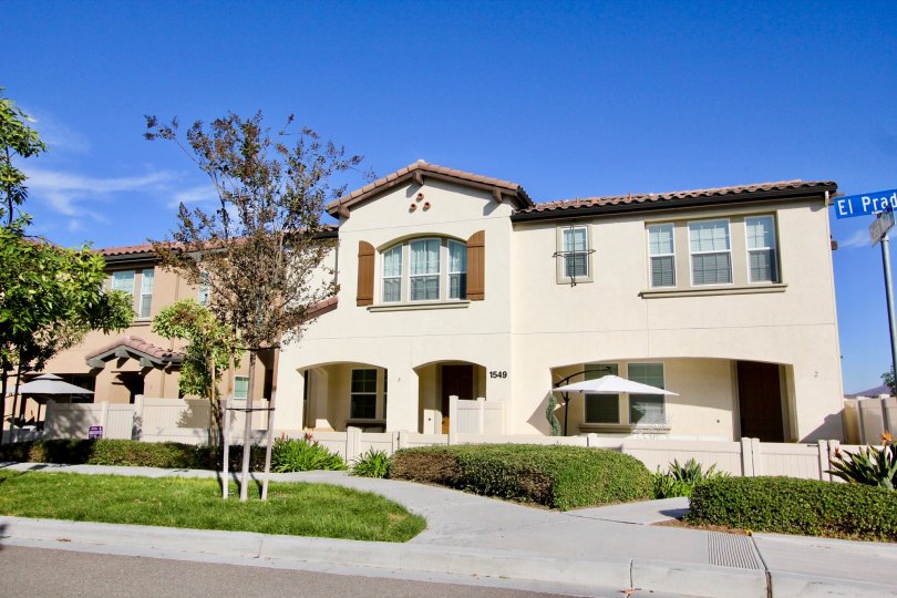 Trees in front Two story white home with hedges & grass located at Avalon in Chula Vista CA
