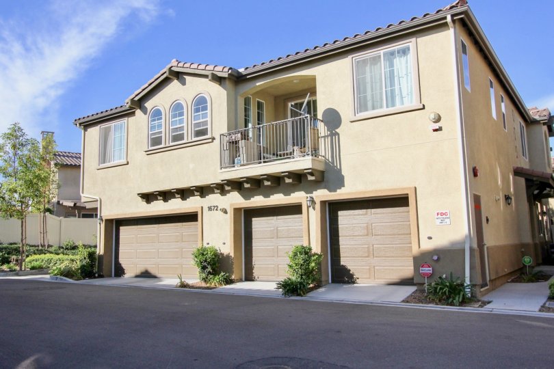 Building with 3 garages and a balcony on a sunny day.