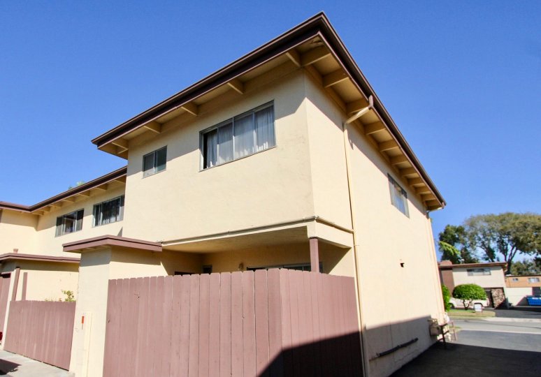 A two story brown building with a wooden pink fence at Holiday Gardens in Chula Vista California