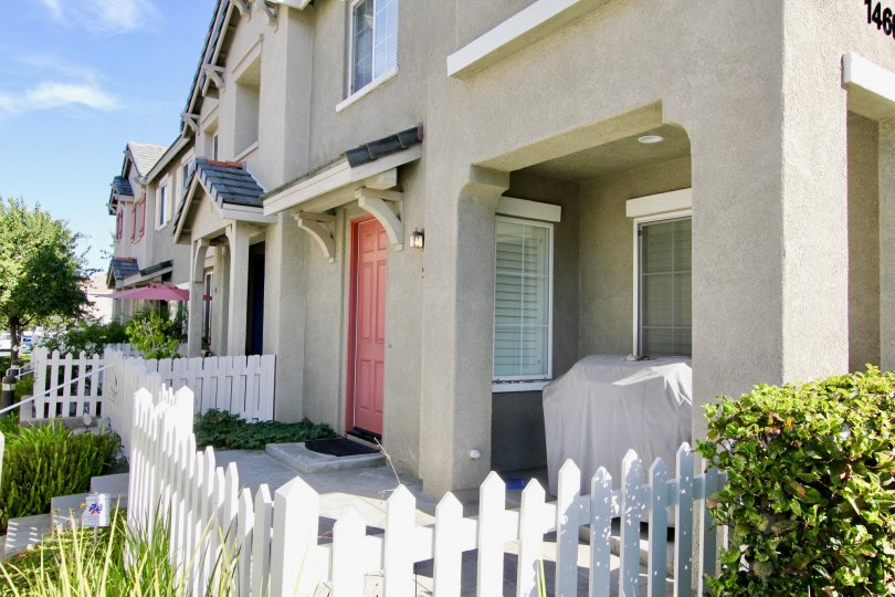 A sunny day in the area of Monet, outside, white picket fence, bush, door, condos