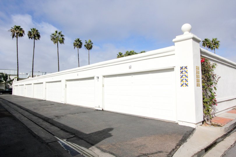 A row of white garage doors with some palm trees in the background during a sunny day in Antigua Court, Coronado, CA