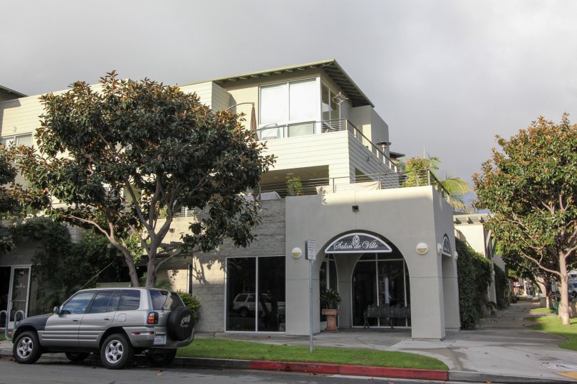 A corner with a shop, a parked car and a tree during a cloudy day in Crownview, Coronado, CA