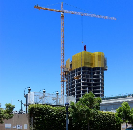 A tall crane being used in the constructions of a building in Pacific Gate on a beautiful day.