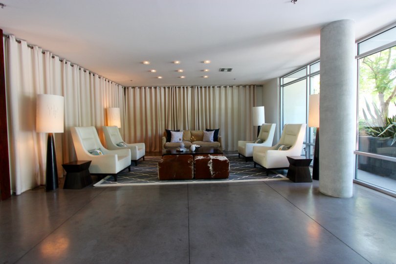 Modern living room with concrete pillars and flooring and large bay windows in the community of Aloft, San Diego, CA