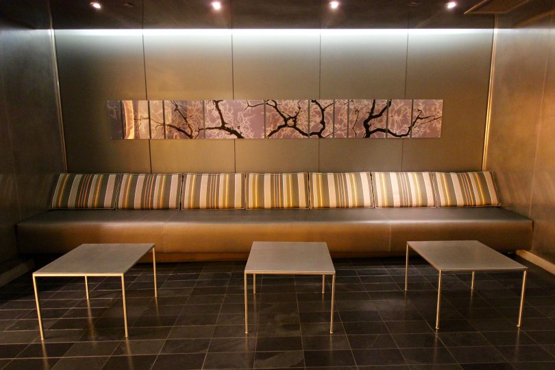 A unique looking tan wall and couch with striped throws and tables.