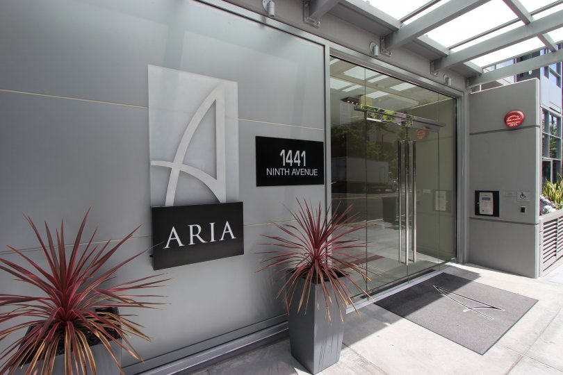 The entry doors to Aria with welcoming plants and signage.