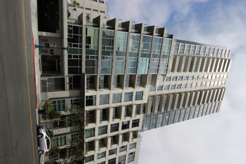 A radiant and bright day at The Aria showcasing the impressive and sophisticated architecture of the tall and magnificent building with a view of the street and parked cars