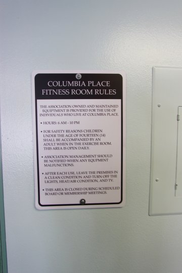 Black and white sign posted to a white wall inside Columbia Place in Downtown Sand Diego CA