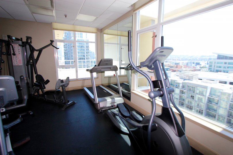 Well-appointed fitness room with massive windows overlooking the city at Diamond Terrace in Downtown San Diego, California.