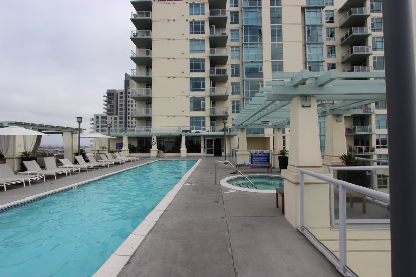 A long narrow pool sits on a rooftop terrace on a cloudy day at Discovery condos